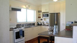 A modern kitchen with white cabinets, stainless steel appliances, a built-in microwave, and a refrigerator.