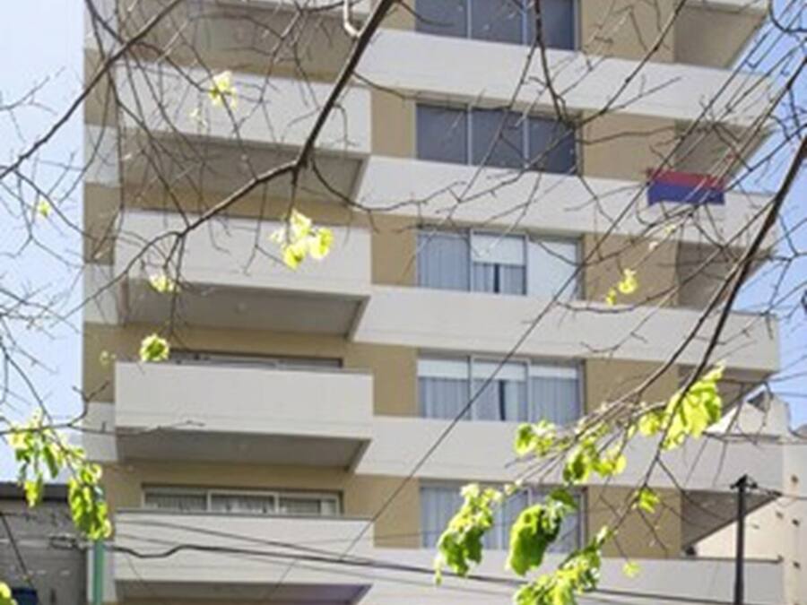 Um edifício de vários andares com fachada plana, várias varandas e entrada no nível da rua.