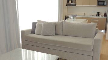 A modern living room with a sofa, a coffee table, and a kitchen in the background.