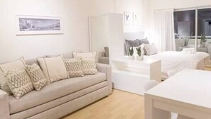 Una habitación de hotel moderna con sofá, mesa de comedor y cama.
