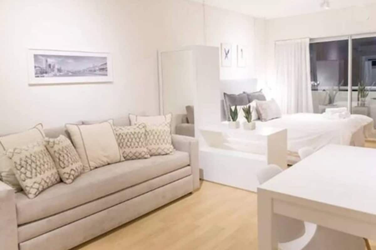 Una habitación de hotel moderna con sofá, mesa de comedor y cama.