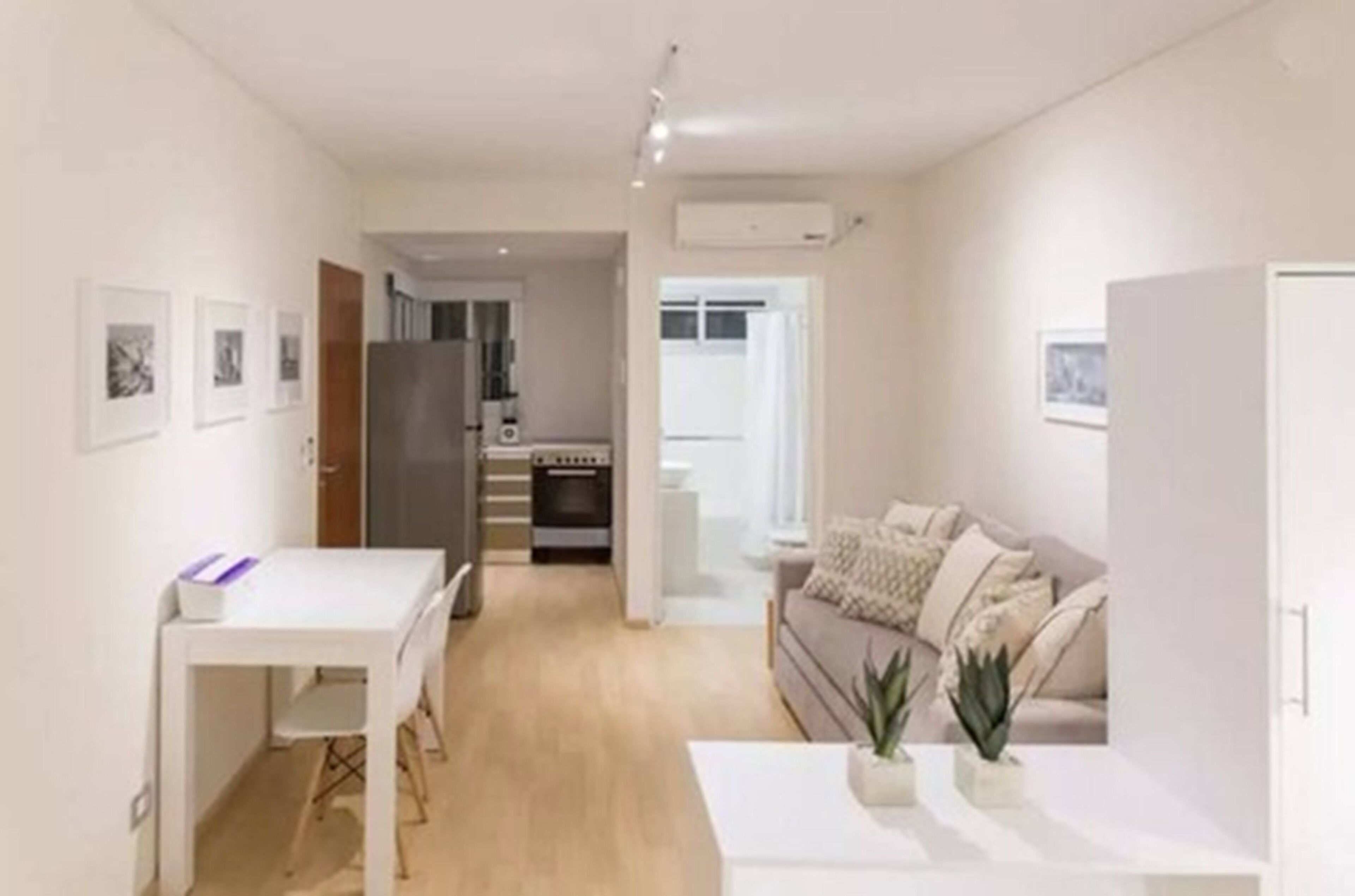 A modern apartment with a dining area, a sofa, and a kitchen in the background.