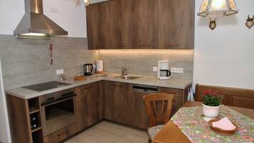 Eine Küche mit Holzausstattung, einer Edelstahl-Dunstabzugshaube, einem Spülbecken, einem Geschirrspüler und einem Essbereich mit Tisch und Stühlen.