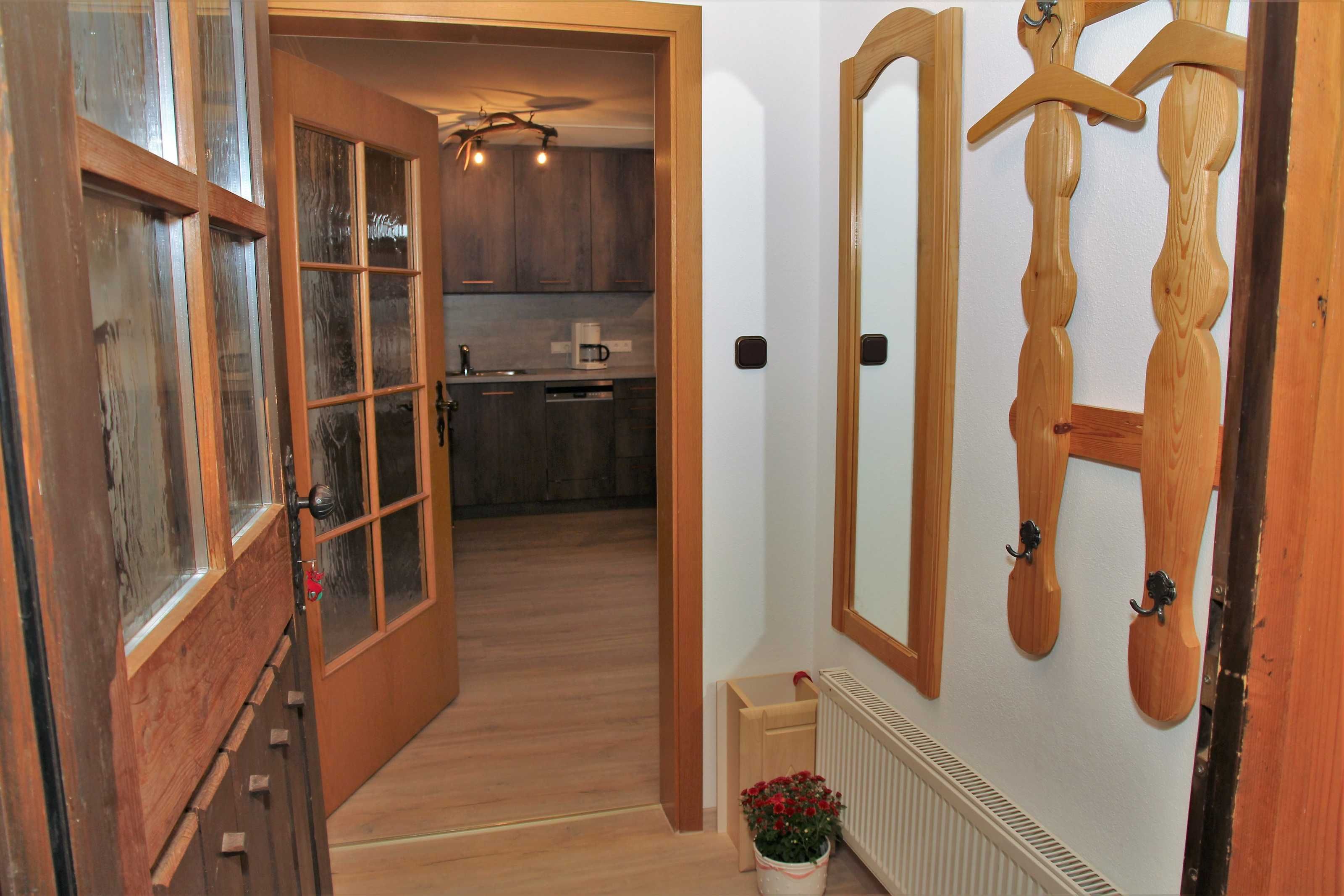 Eine Holztür führt zu einer Küche mit eingebautem Backofen und einem hängenden Holz-Kleiderhaken.