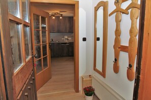 A wooden-framed door leading to a kitchen with a built-in oven and a hanging wooden coat rack. - Apartment 2 - Bocksleitnerhof (Wackersberg)
