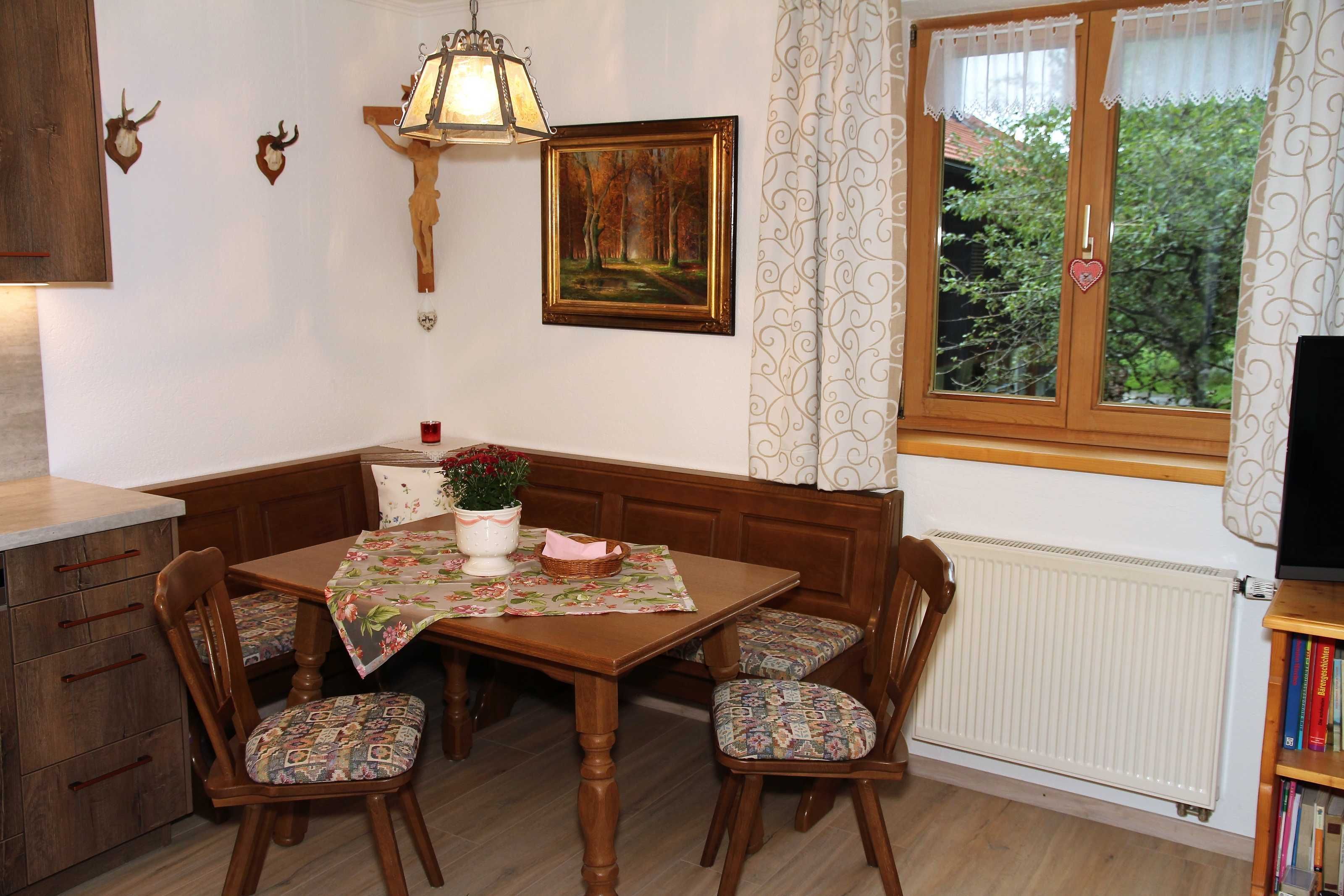 Un coin repas avec une table en bois, des chaises, une lampe, un tableau et une fenêtre avec des rideaux.