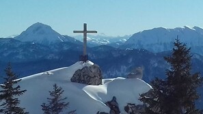 Un sommet montagneux enneigé surmonté d’un monument en forme de croix.
