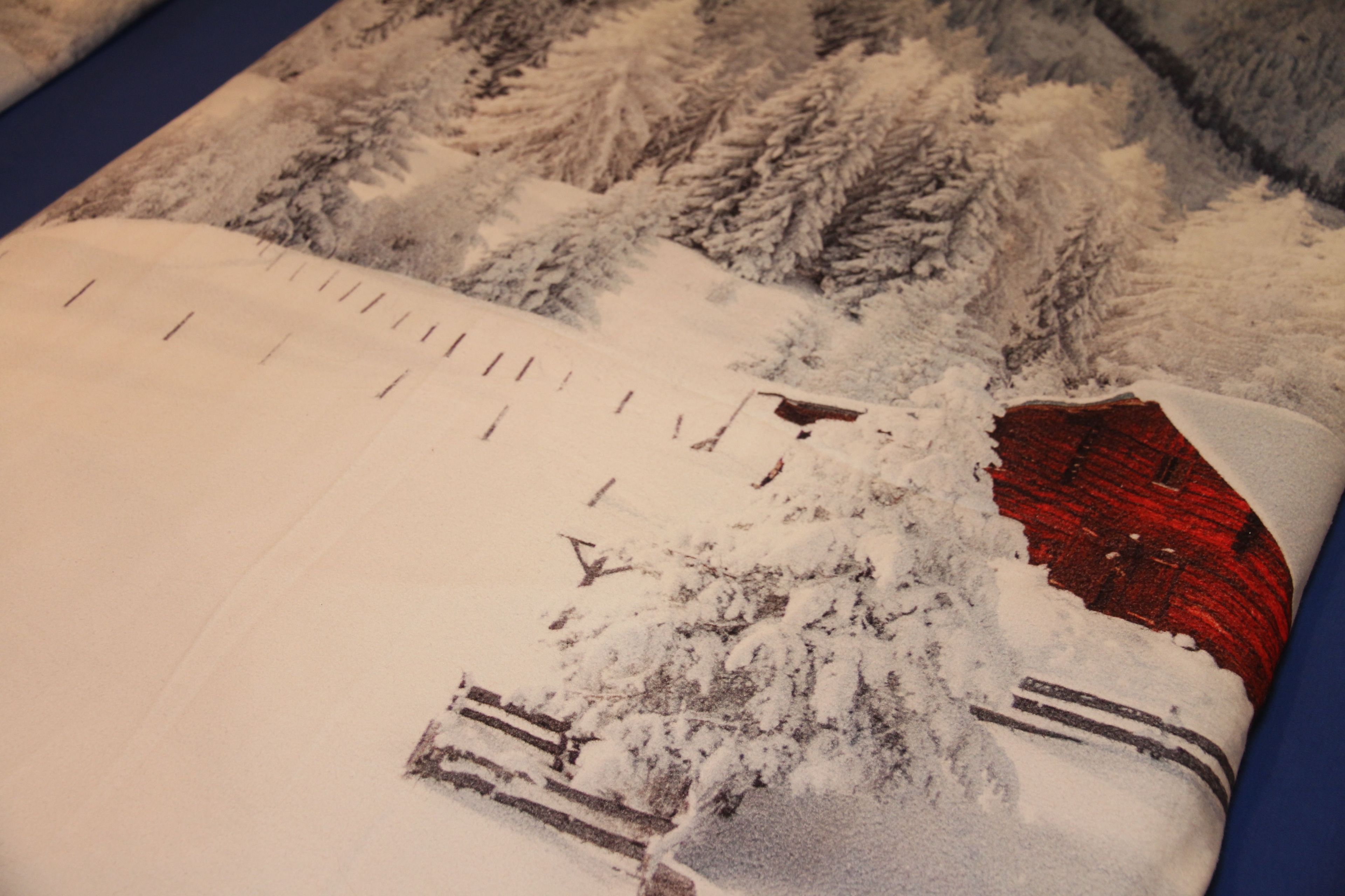 A notebook with a snow-covered landscape illustration, a red object, and a wooden fence.