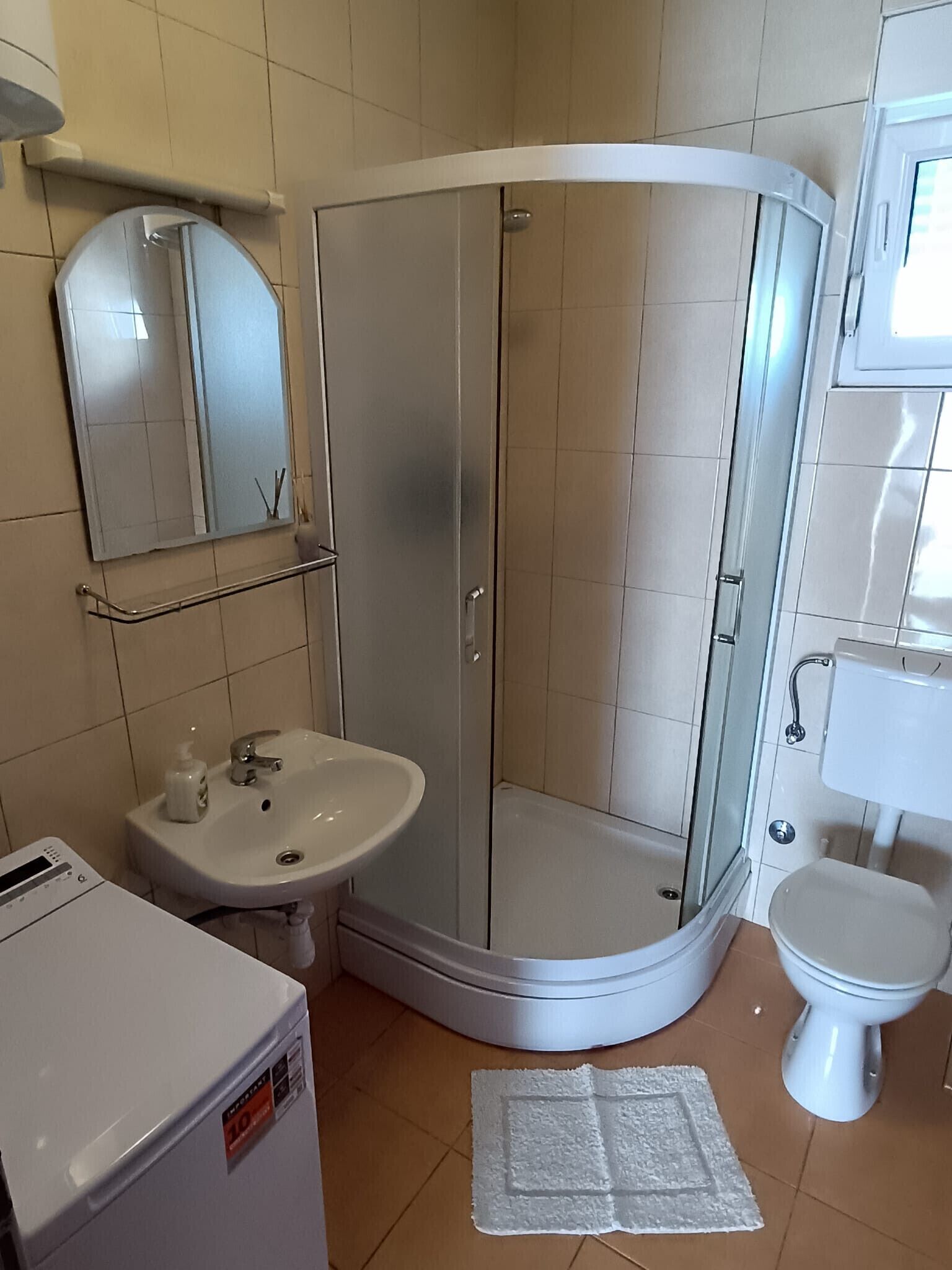 Un baño con ducha de vidrio, lavabo, inodoro y espejo.