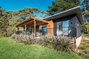Uma casa moderna com pérgola de madeira, janelas amplas e um jardim bem cuidado.