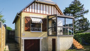Une maison à deux étages avec une façade en bois, un garage et un petit balcon agrémenté d’une chaise et d’une table.