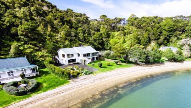 Une propriété située sur la côte, comprenant une grande maison, une plage et une forêt dense.