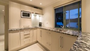 Une cuisine moderne avec des armoires de couleur beige, un comptoir en granit et une fenêtre donnant sur l’extérieur.