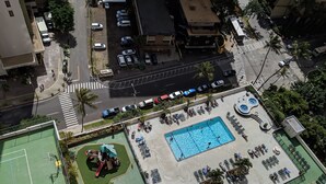 Vista aérea de un área recreativa con piscina, tumbonas, parque infantil y cancha de baloncesto.