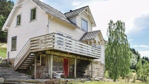 Ein zweistöckiges Haus mit Balkon und Natursteinfassade.