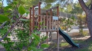 Children can play on the playground's slide and climbing area, supervised by adults.