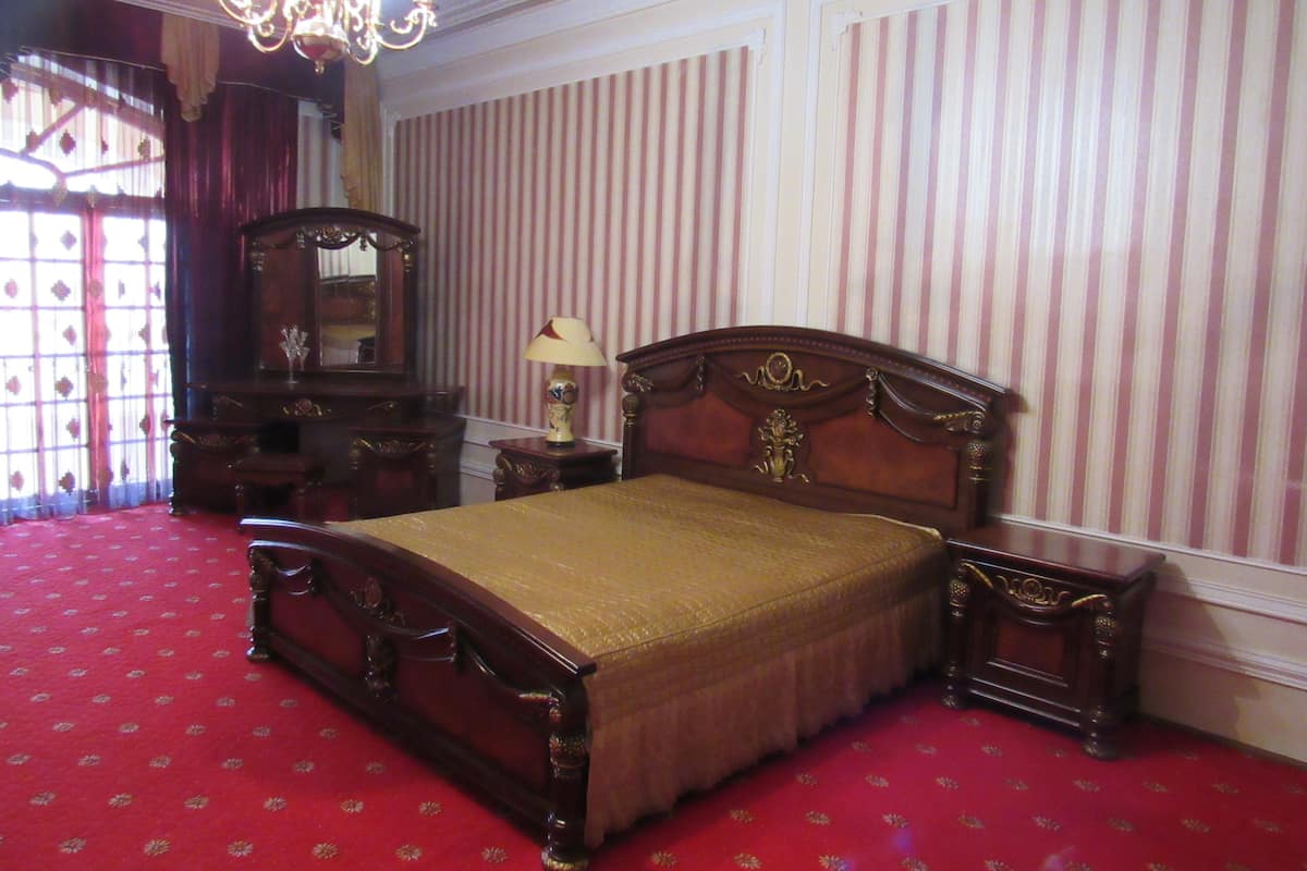 A classic bedroom with a four-poster bed, a nightstand, a dresser, and a chandelier.