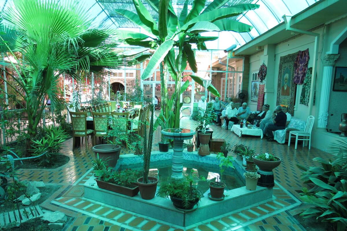 A spacious indoor garden with a variety of potted plants and a central fountain.