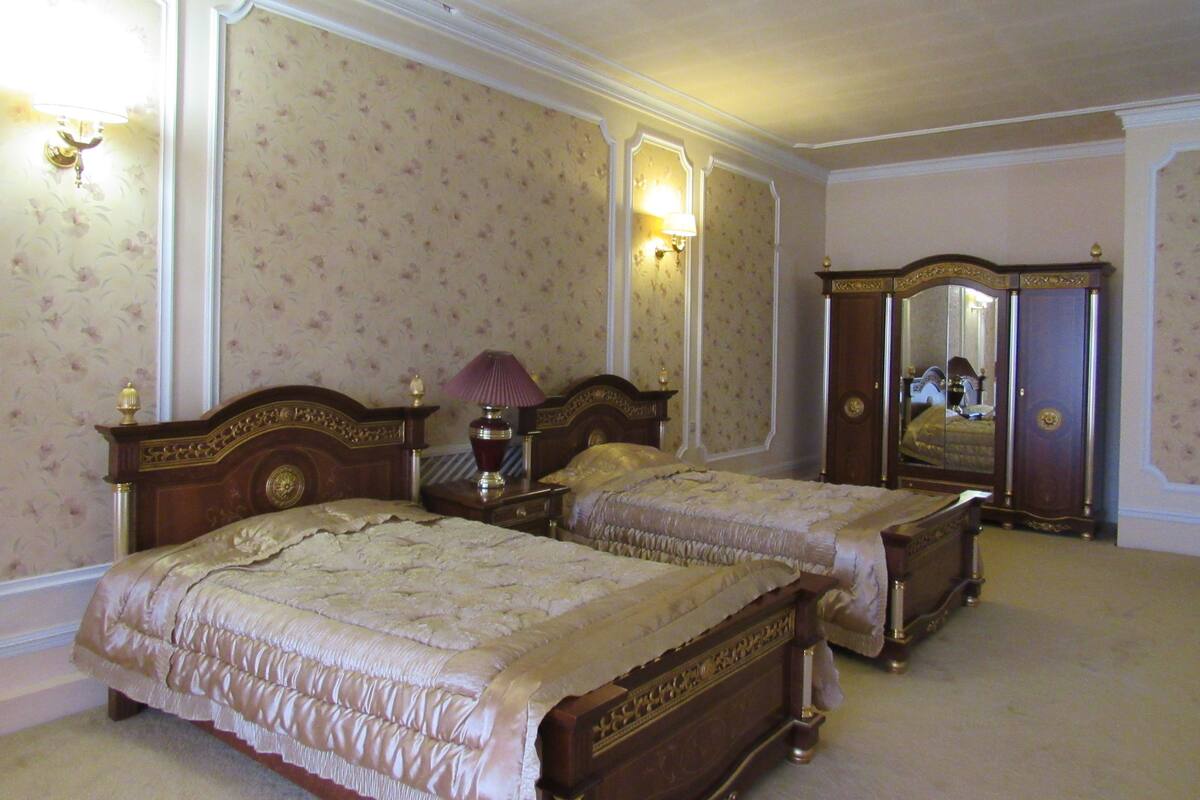 A bedroom with two beds, a dresser, and a mirror.