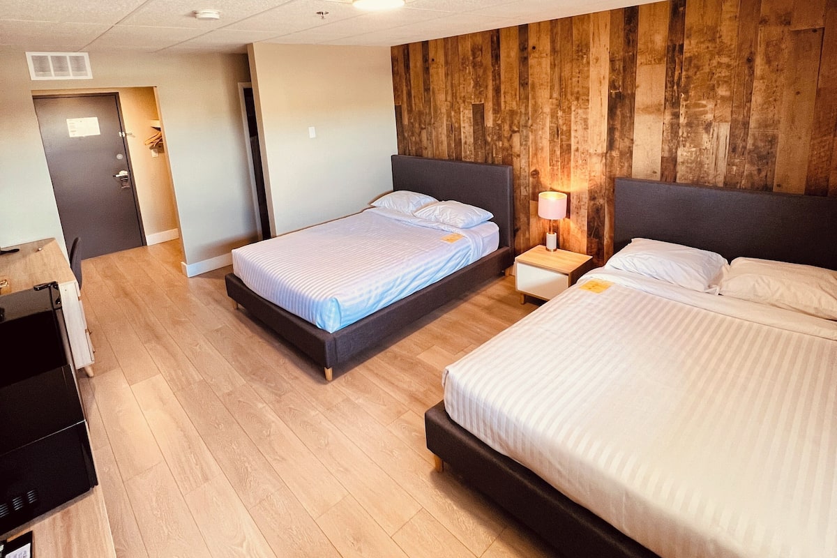 Une chambre d’hôtel moderne avec deux lits, un mur recouvert de lambris en bois et un plancher en bois.