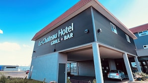 The exterior of Le Chateau Hotel with a sign indicating a Grill + Bar. - Camrose LeChateau Hotel (Camrose)