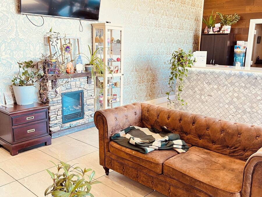 Un salon chaleureux avec un canapé en cuir marron, une cheminée en pierre et un téléviseur fixé au mur.