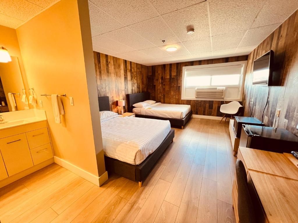 Habitación de hotel con piso de madera, una cama, un escritorio y un televisor.