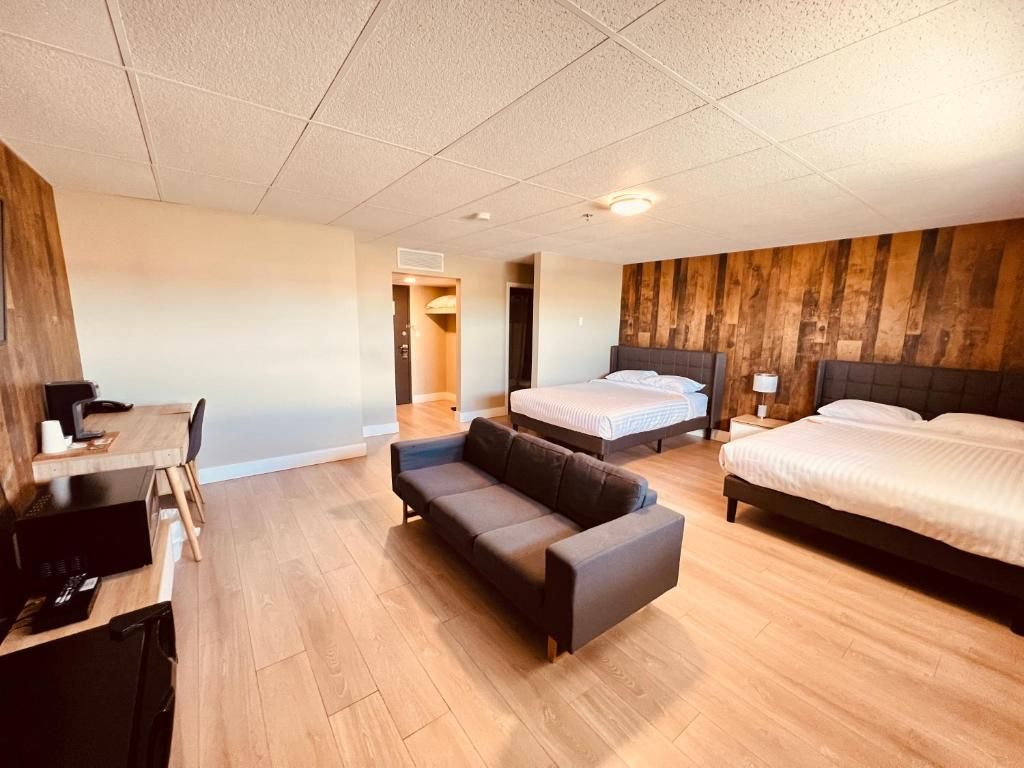 Una camera d'albergo con divano, due letti, una scrivania e una parete decorata in legno.