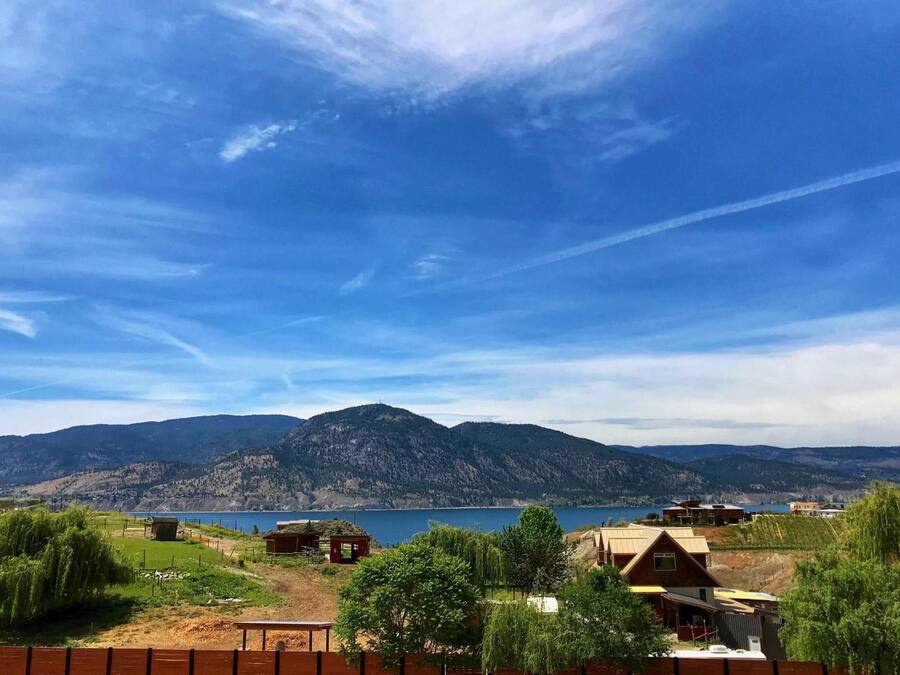 Une propriété au bord du lac, avec des chalets, une vue sur les montagnes et un ciel dégagé.