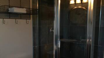 Un baño con cabina de ducha de vidrio, inodoro y toallero con toallas.