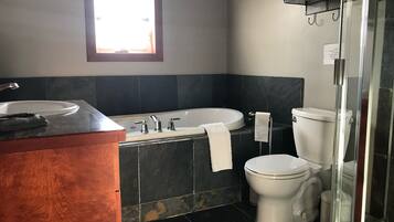 Et badeværelse med vask, badekar, toilet og bruseniche i glas.