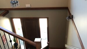 A wooden staircase with a handrail, a wall-mounted air conditioner, and a window with natural light. - Wesbert Winery & Guest Suites (Penticton)