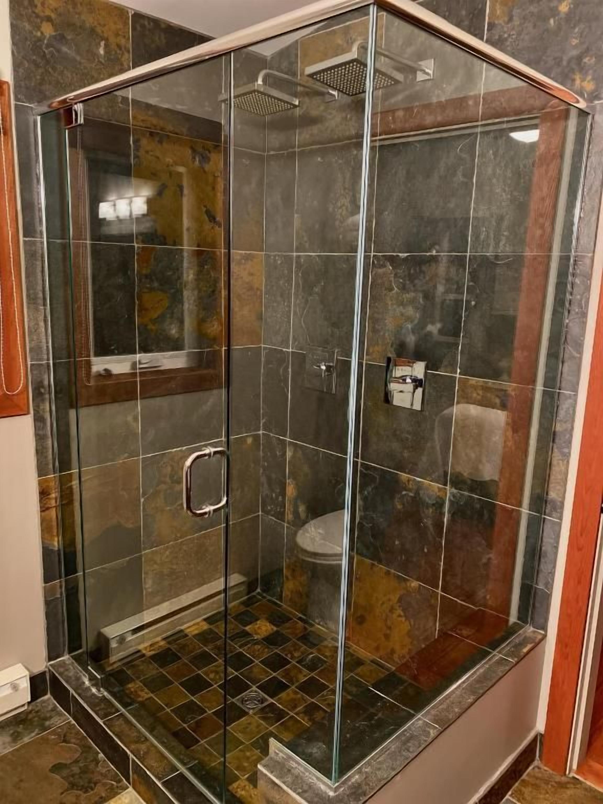 A glass-enclosed shower stall with a tiled floor and a showerhead.