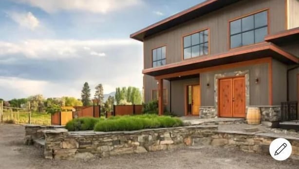 A modern two-story house with a stone foundation, large windows, and a wooden front door. - Wesbert Winery & Guest Suites (Penticton)