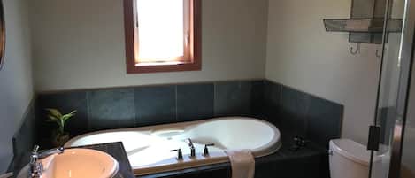 Un baño con una bañera grande, un lavabo e inodoro.