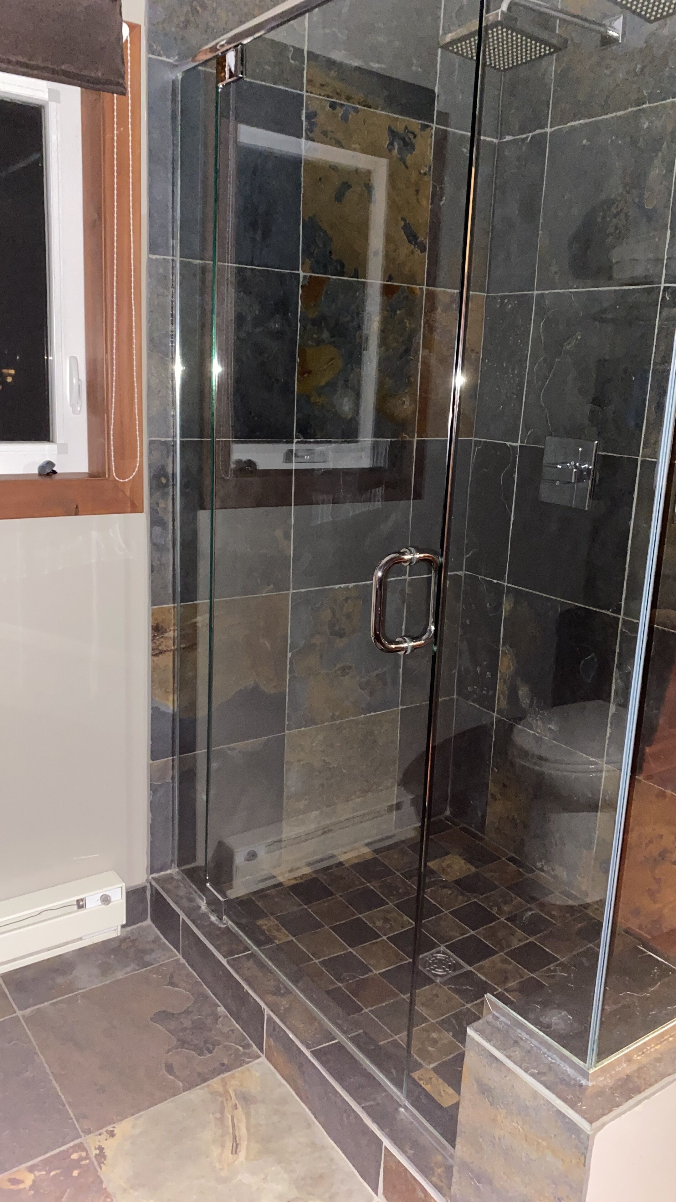 A glass-enclosed shower area with a tiled floor and a visible showerhead.