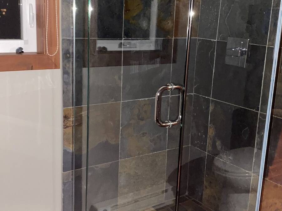 A glass-enclosed shower area with a tiled floor and a visible showerhead.