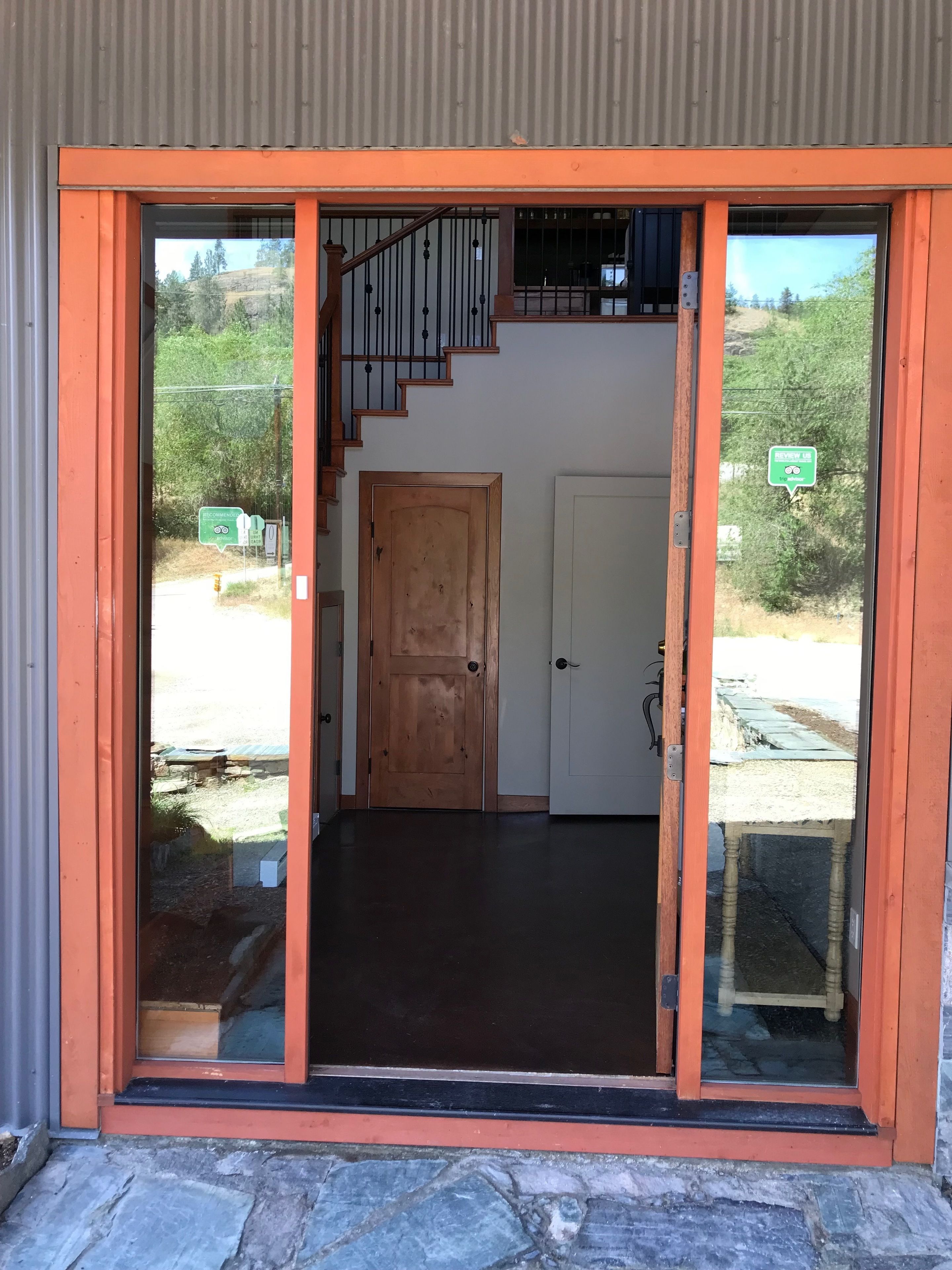 Entrada de edificio con puerta de madera, puerta de cristal y una escalera que sube a un nivel superior.