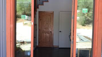 Entrada de edificio con puerta de madera, puerta de cristal y una escalera que sube a un nivel superior.