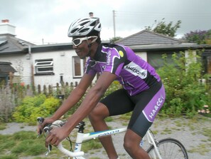 En cyklist i lilla og sort tøj, der cykler på en hvid cykel.