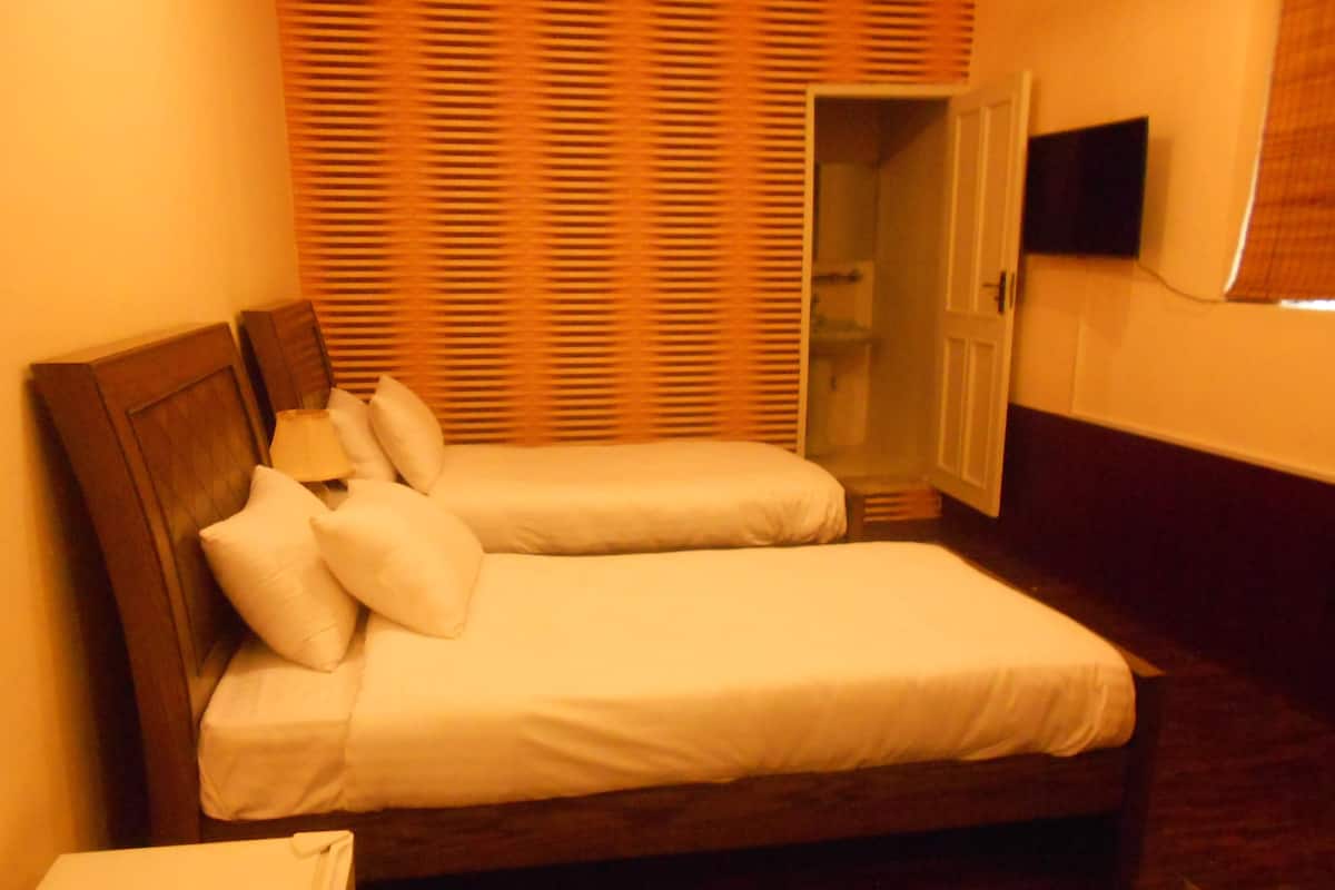 A double bed with white linens, a wooden headboard, and a bedside table.