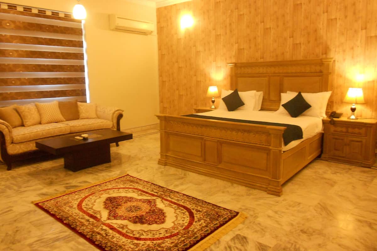 A hotel room with a large bed, a sofa, a coffee table, and a decorative rug.