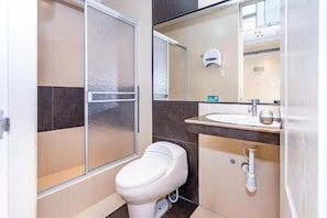 Un baño con inodoro, lavabo y zona de ducha.