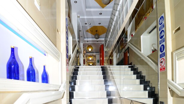Una escalera en un edificio de diseño moderno, con barandilla y piso de baldosas.