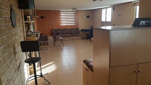 A spacious living area with a sofa, a dining table, and a kitchen area with a refrigerator. - Ahla Vert View (Sebaal)