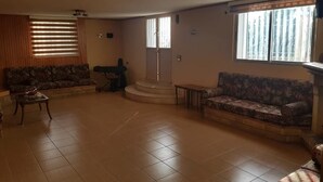 A spacious living room with two sofas, a coffee table, and a staircase leading to an upper floor. - Ahla Vert View (Sebaal)
