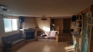 A spacious living room with a fireplace, a sofa, and a coffee table. - Ahla Vert View (Sebaal)