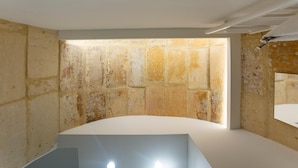 A room with a white reception desk, a stone wall, and a small window. - Ad Maiora - Desing Rooms (Ragusa)