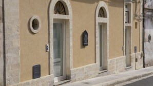 A building with arched doorways and a sign indicating a hotel. - Ad Maiora - Desing Rooms (Ragusa)