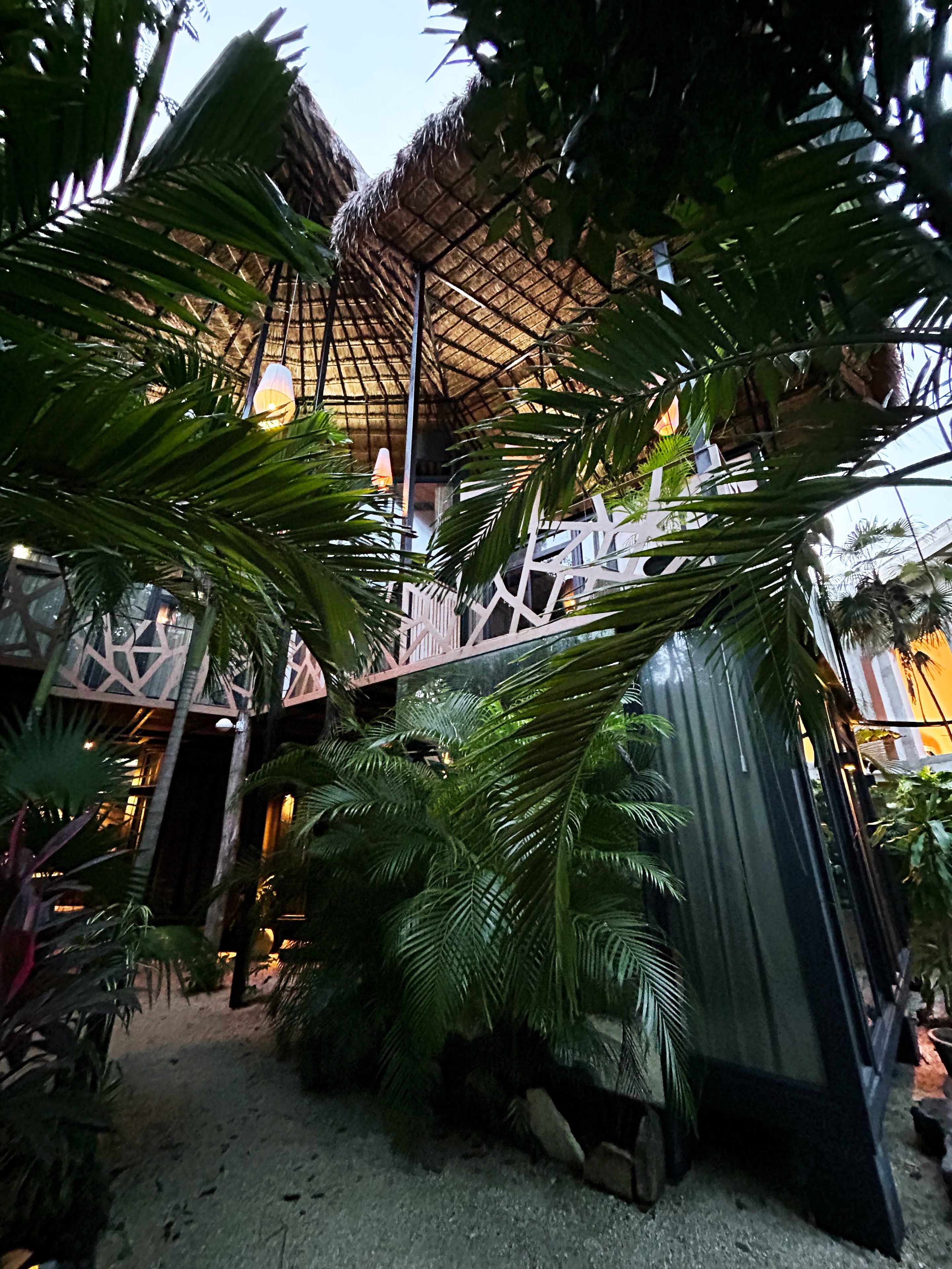 A thatched-roof structure with a wooden deck, surrounded by lush tropical foliage.